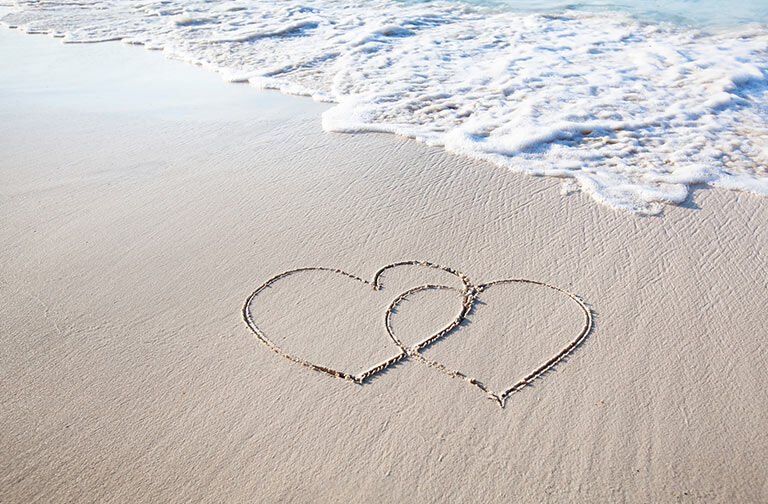 hearts drawn in sand on beach